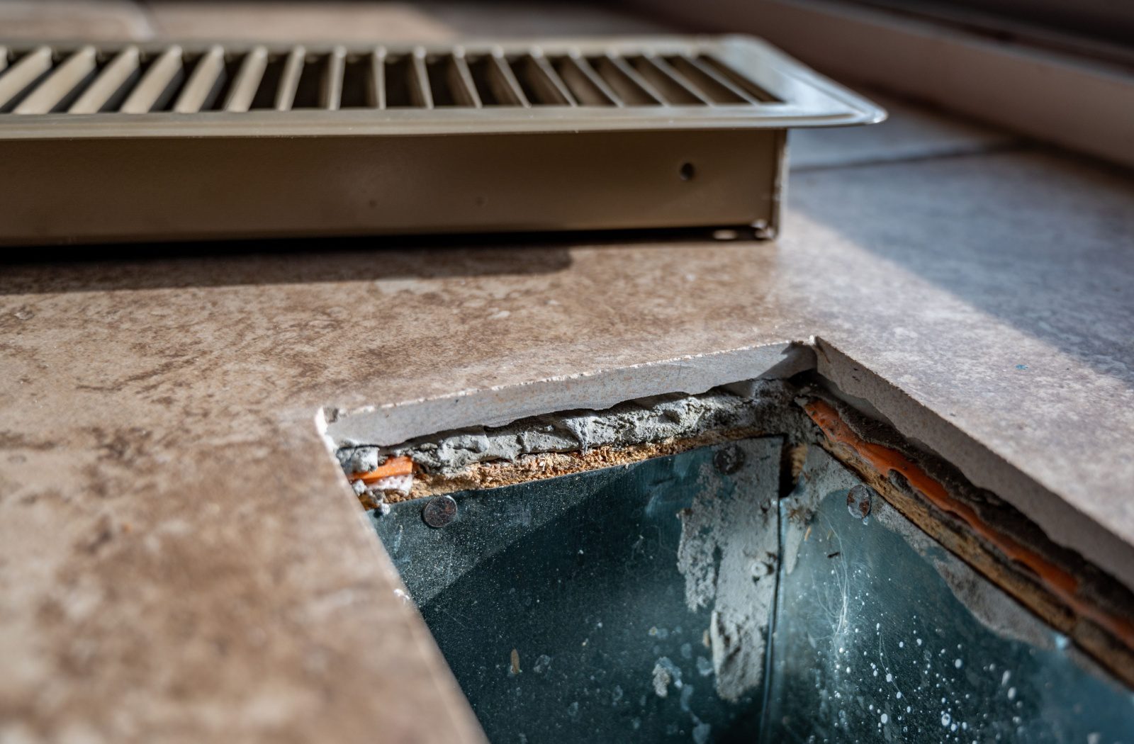 A close-up view of an open floor vent shows debris that's accumulated over time.