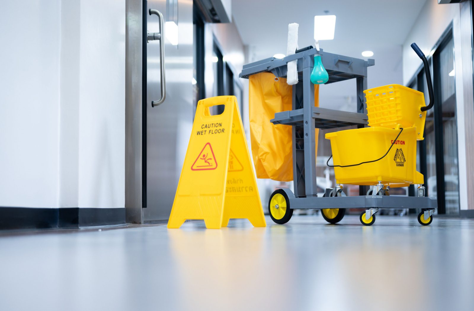 A cleaning cart is parked in an office hallway.