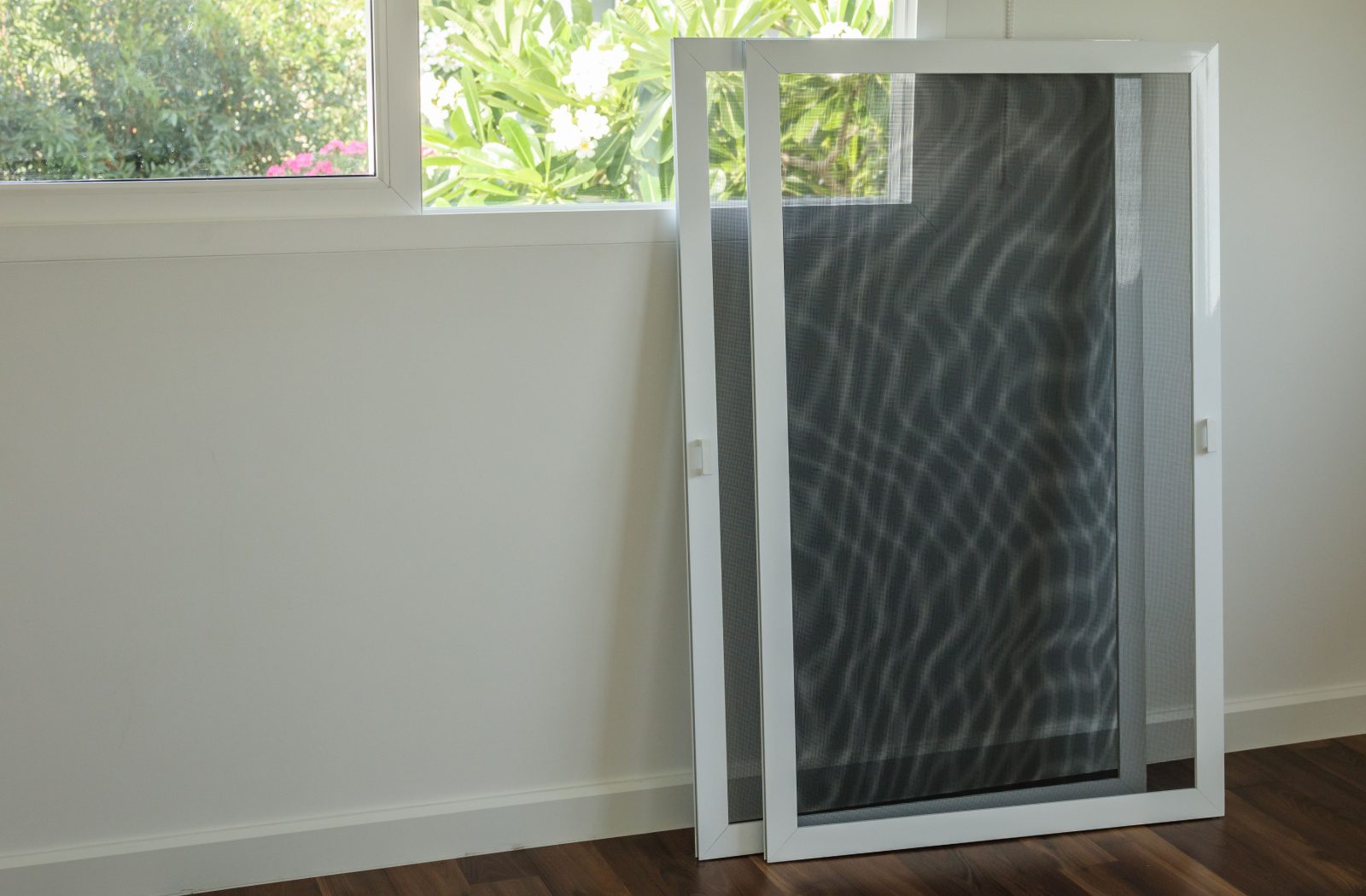 Two window screens leaning against the wall by an open window.